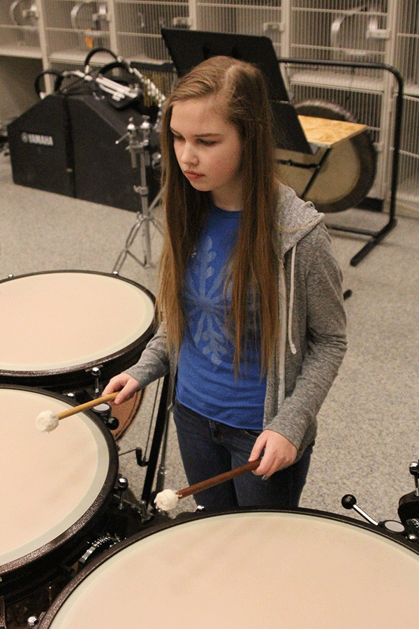 With the booming sounds of her fellow percussionists, freshman Marissa Olin drums on the timpani on Wednesday, March 4. “I like playing [timpani drums],” Olin said. “They’re challenging.” 