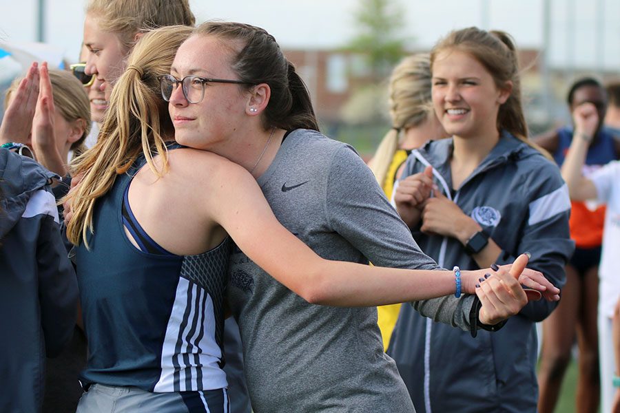 After the 1600 meter run, senior Delaney Kemp hugs freshman Katie Schwartzkopf as she comes off the field. 
