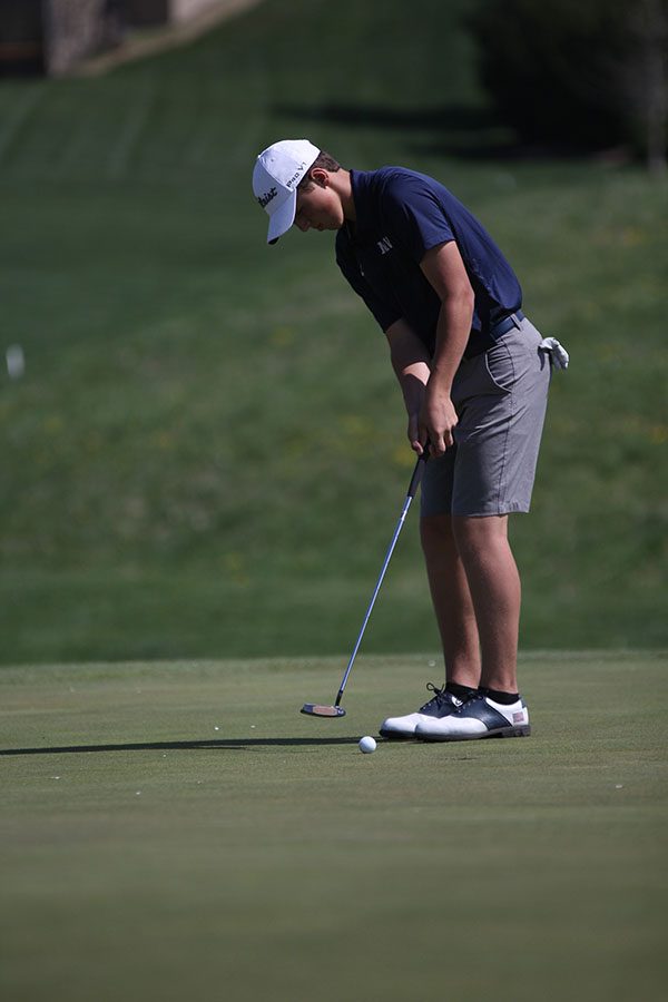 Moving with caution, sophomore Nicklaus Mason puts the ball into the hole.