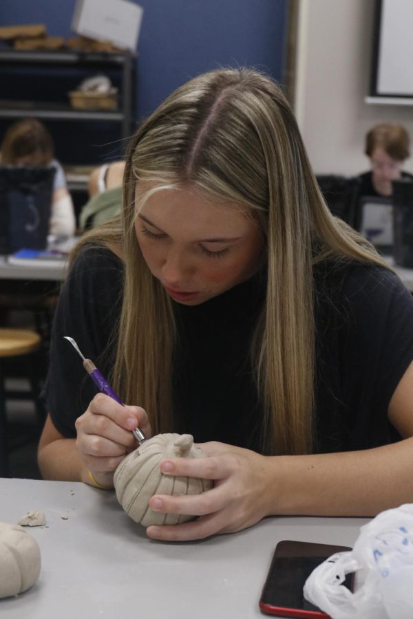 Junior Camryn Kunik carves her clay pumpkin project Monday, Sept. 19 in Erica Matyak’s Ceramics  I class.