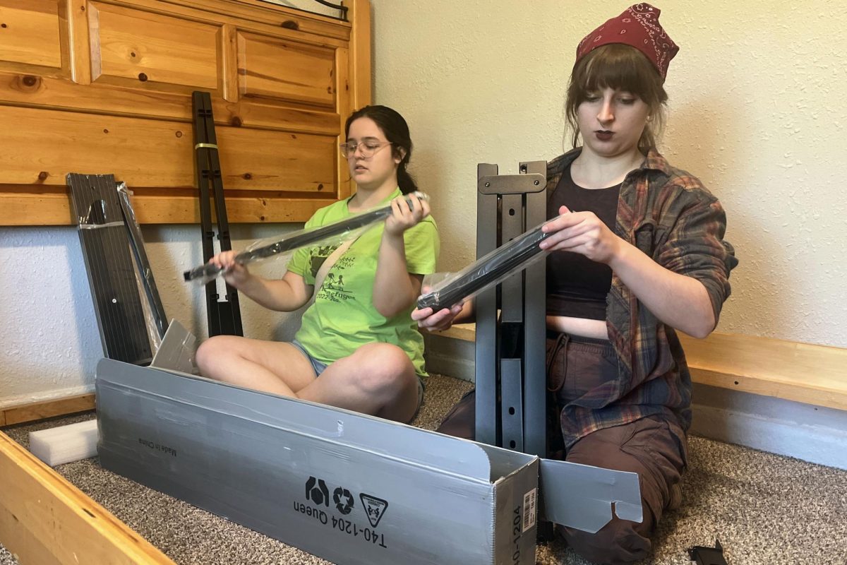 Youth for Refugees co-president Anna Zwahlen and Youth for Refugees secretary sophomore Quin Peters unpack materials for a bed frame.