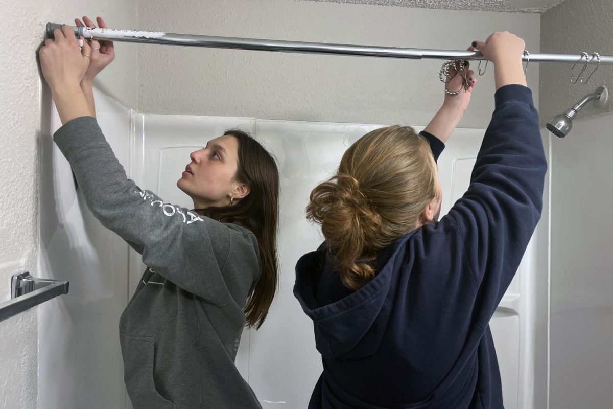 Seniors Shelby Kindt and Gwen Heideman work together to add rings to a shower rod.