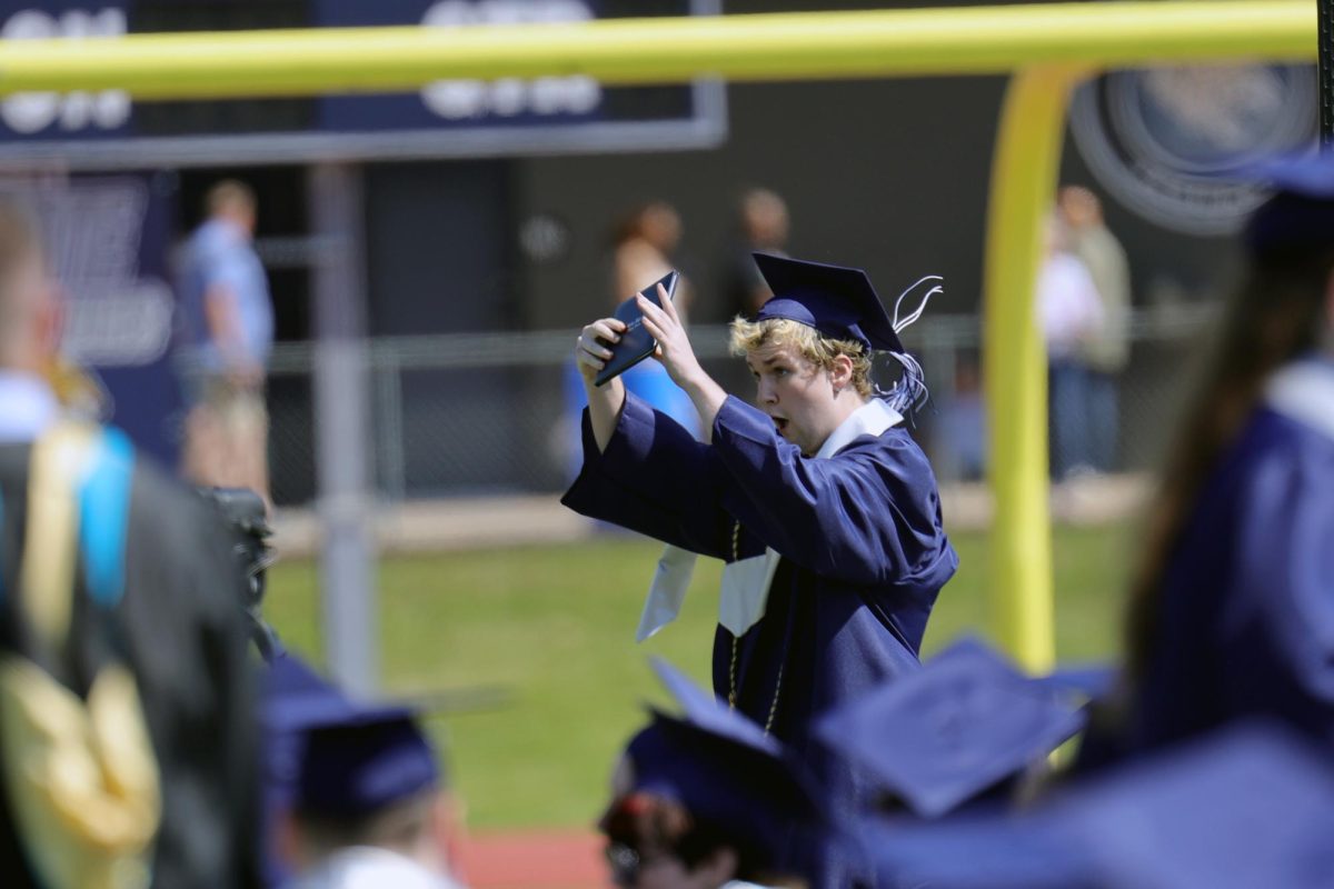 After receiving his diploma, graduate Nate Gardner holds it in the air to family in the stands.