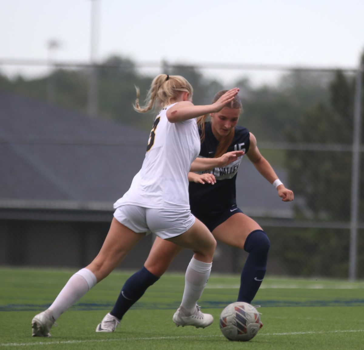 In an attempt to keep control of the ball, junior Kate Martin kicks the ball past her opponent.