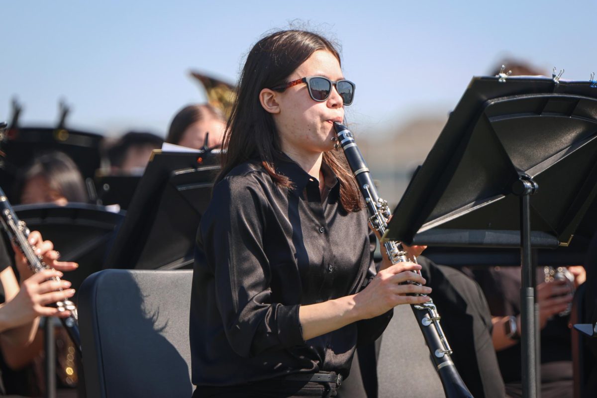 Focused on her sheet music, junior Sophia Hsu plays in the band during graduation. 