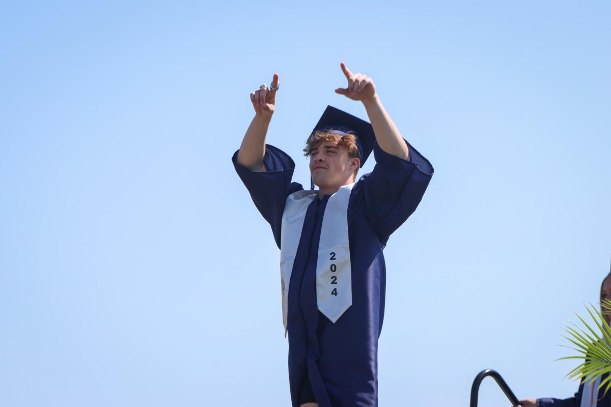 Pointing towards the stands, senior Ryan Deverill walks across the stage.
