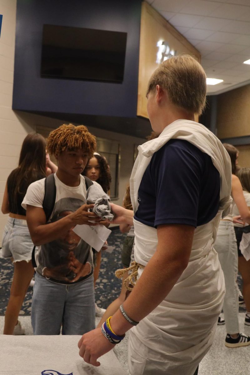 At the end of freshman orientation, junior Elliot Fischer hands a MV T-shirt to an incoming freshman.