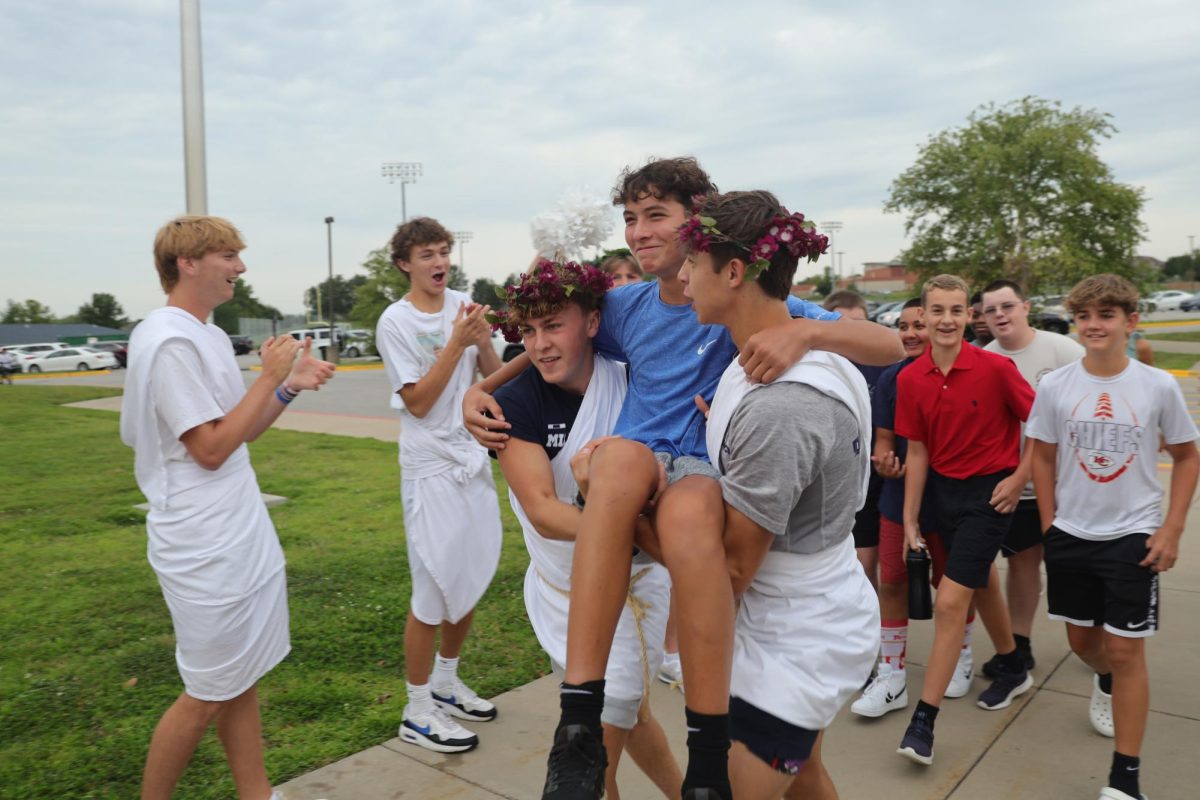 Juniors Gavin Hurt and Blake Jay carry a freshman boy through the crowd to the entrance.