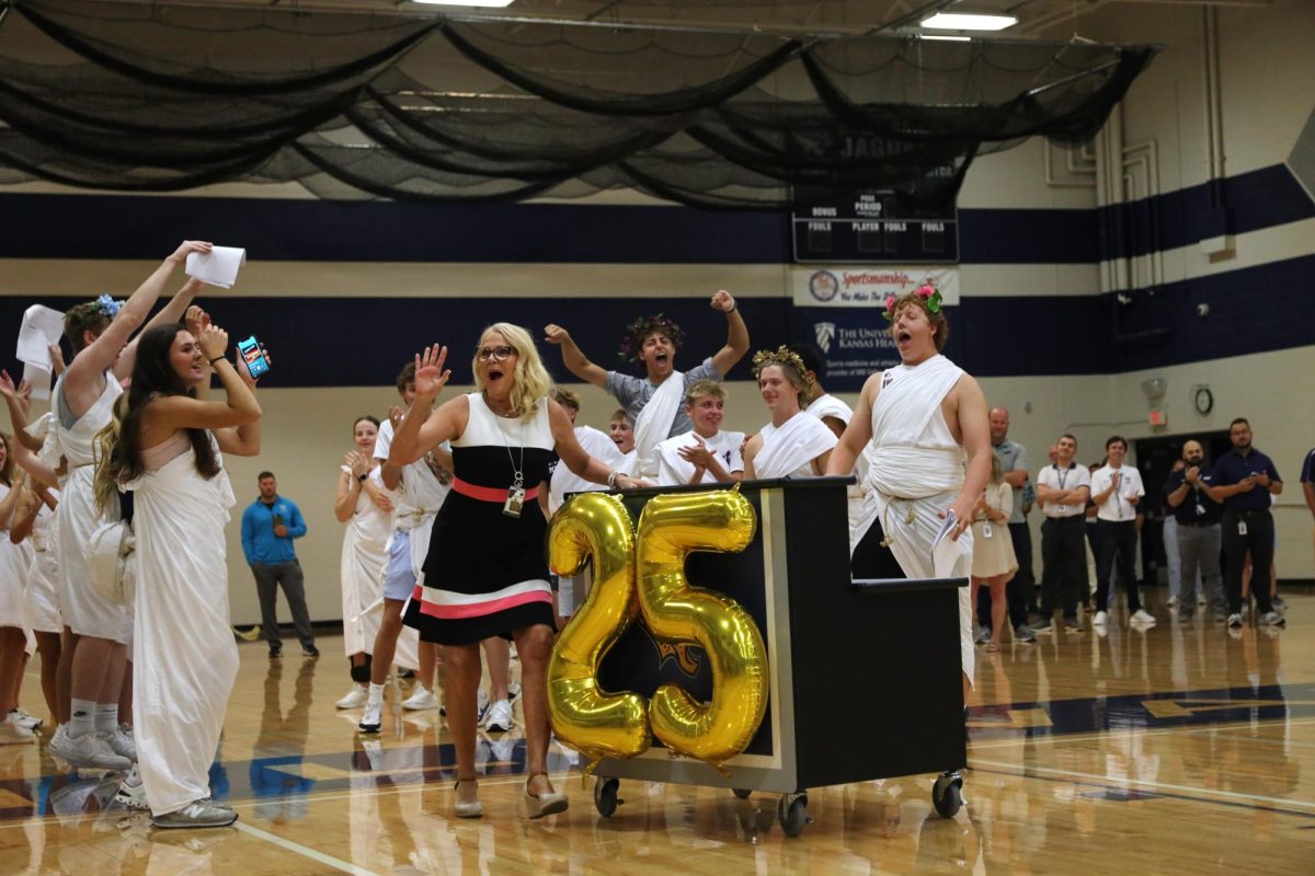 With her arms in the air, principal Dr. Holder prepares to welcome the freshmen during the pep assembly.