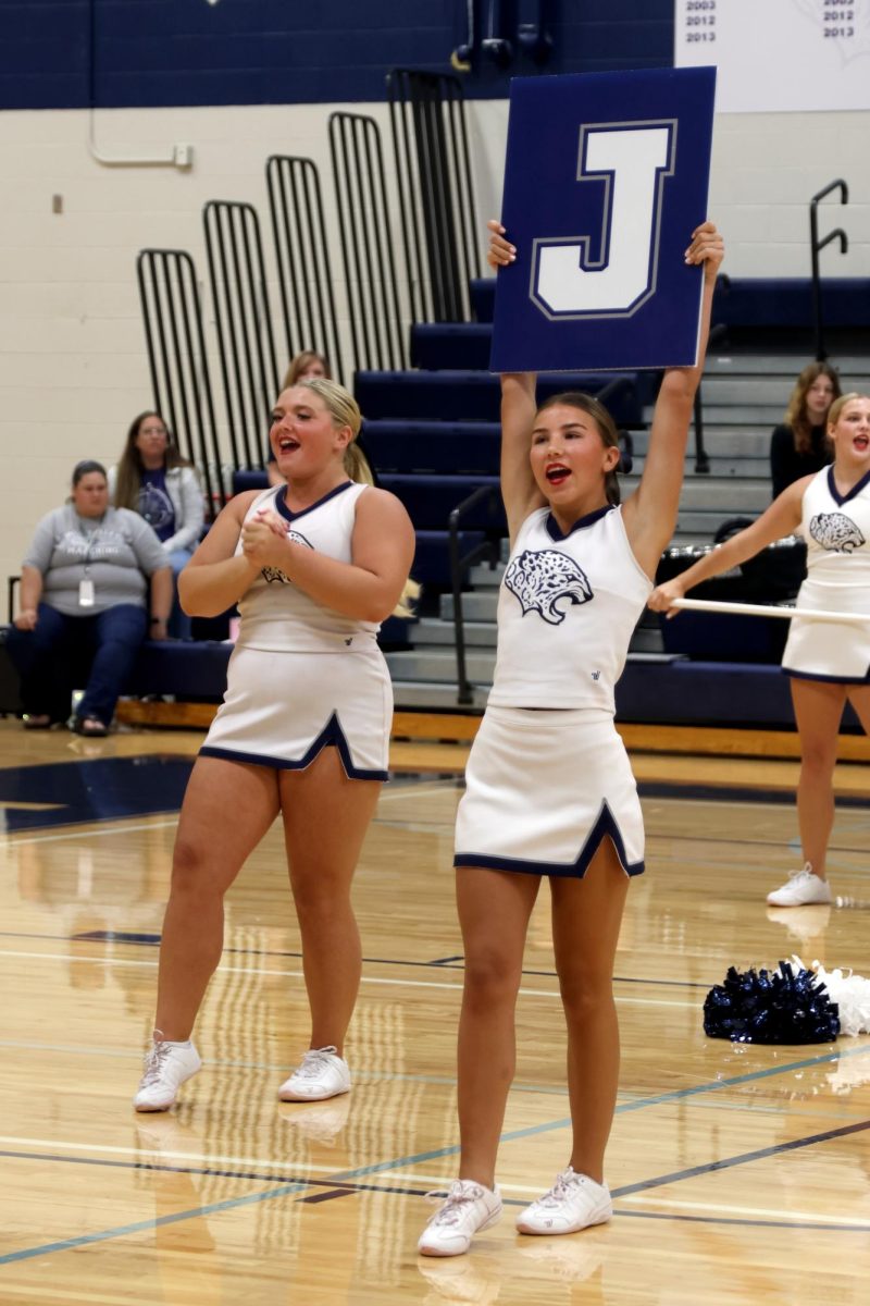 Cheering with the crowd, junior Sydney Epperson holds a sign.