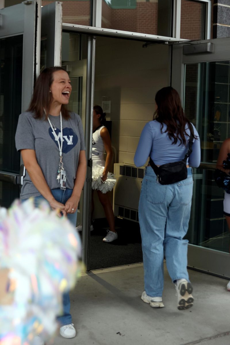 Smiling, media center specialist Ashley Agre greet freshmen.