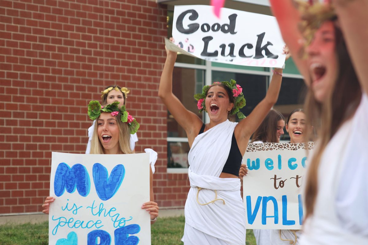 Holding their signs, juniors Corinne Schwindt and Kinley Ruder cheer for the incoming freshmen.