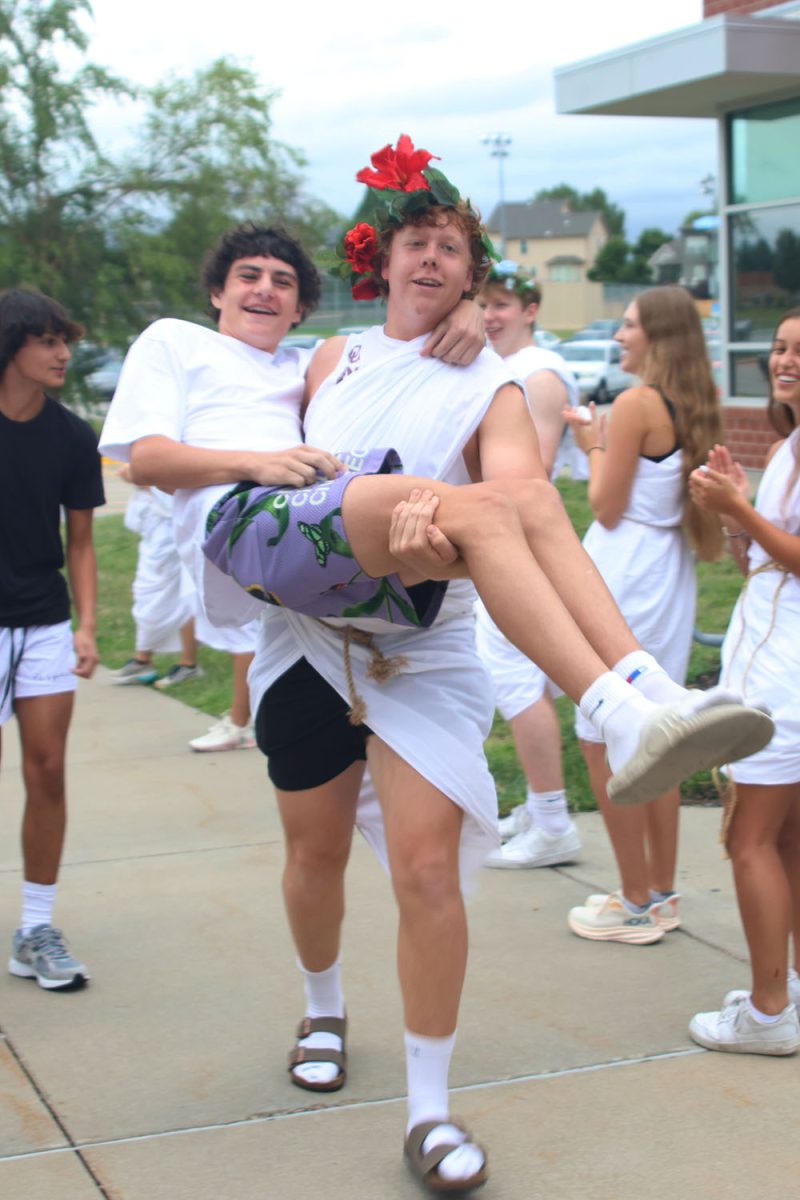 Junior Aiden Lehr welcomes a freshman by carrying him into school.