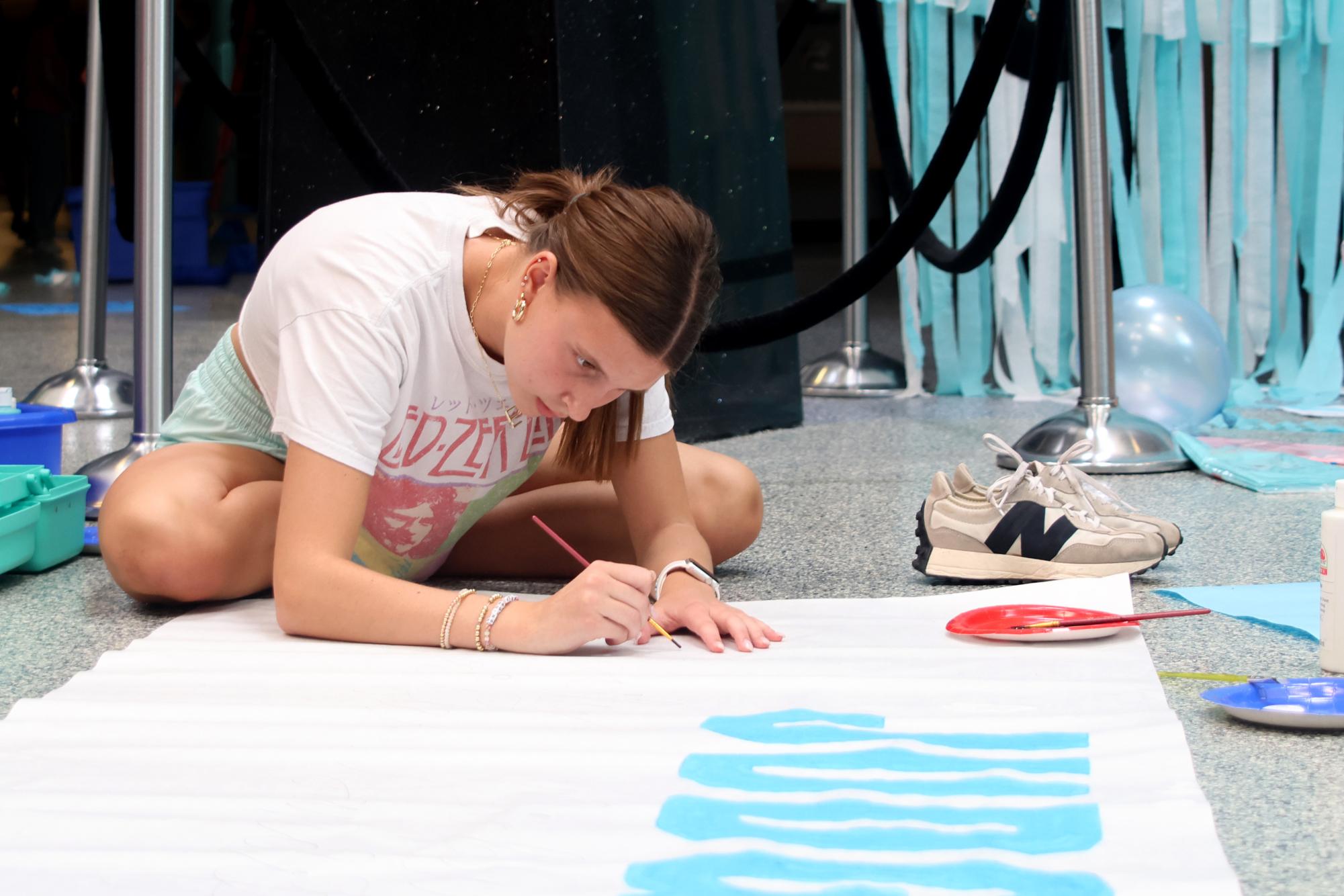 Meticulously, senior Emmie Chezem makes a sign to recognize the judges for the homecoming parade.