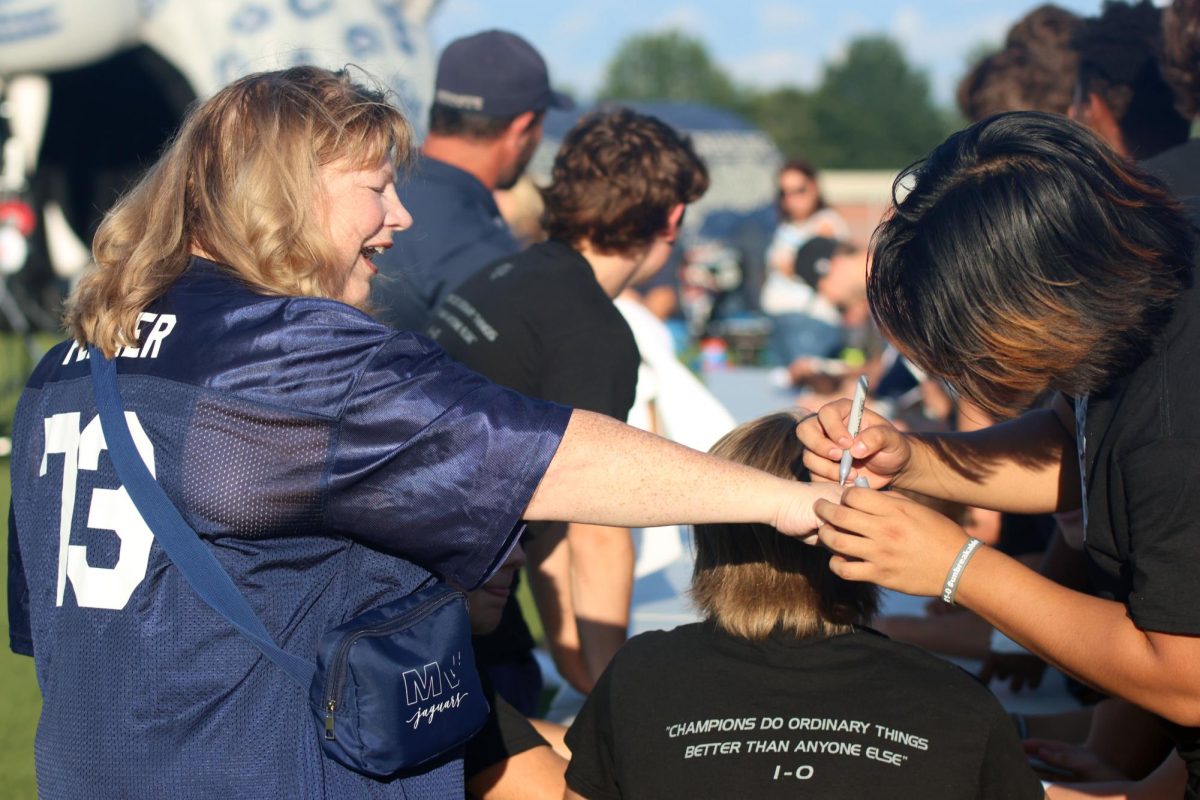 High school football team member signs fan's hand.