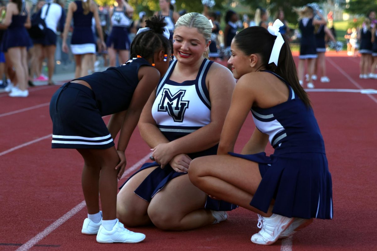 Senior cheerleaders Maddie Dibble and Emersyn Jones give a pep talk to Junior Jag cheerleader.