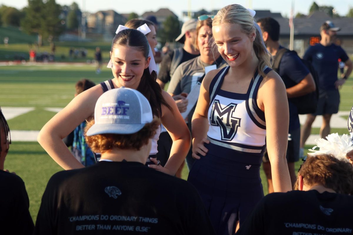 Junior cheerleader Brynlee Sword and Senior cheerleader Riley Maguire wait to get autographs from football players. 