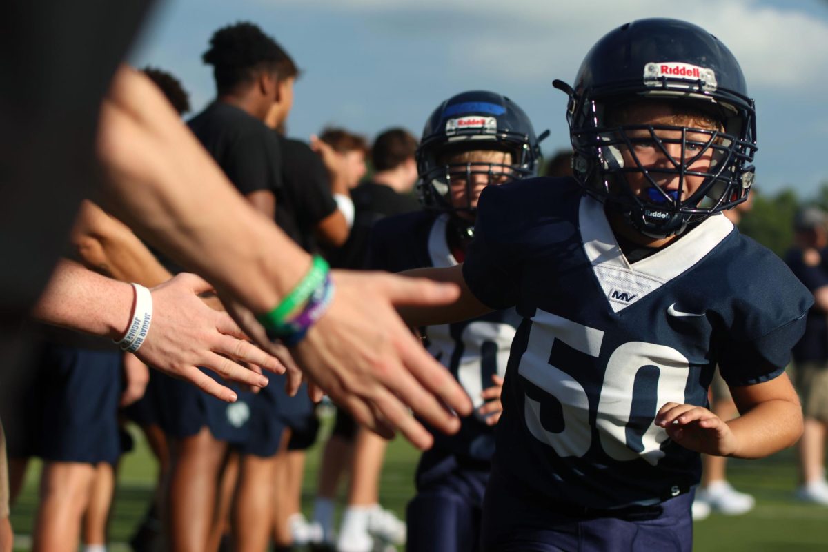 Junior Jag football player gives high fives to outstretched hands. 