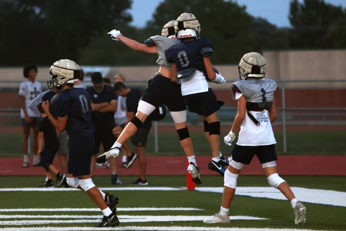 Despite being on different teams 8th grade players celebrate after a touchdown.