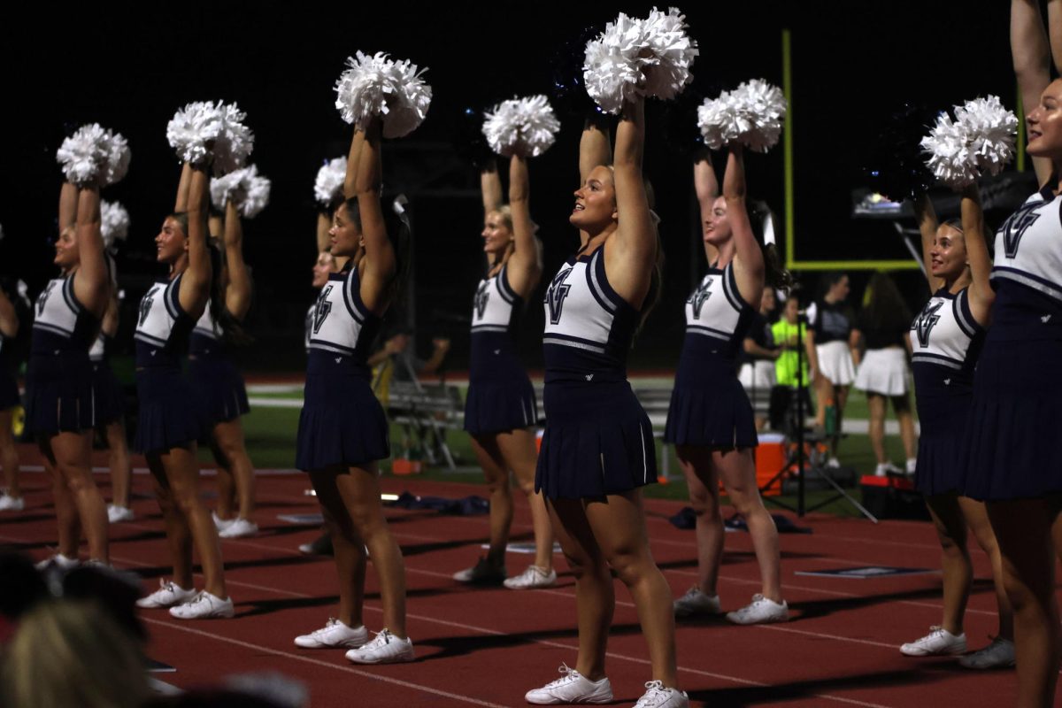 Poms raised, varsity cheerleaders cheer after a touch down.