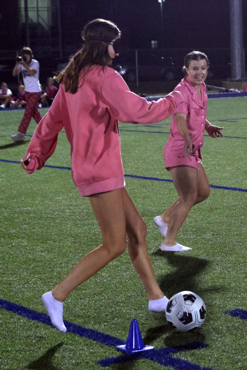 Junior Callie Smouse dibbles the ball blind folded as her partner junior Kyndal Geis directs her.