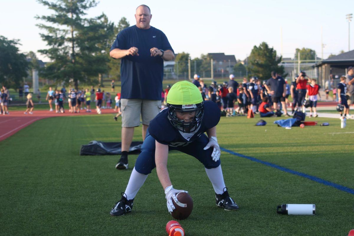 Practicing his snaps, a Junior Jag football player tosses the ball to his coach.