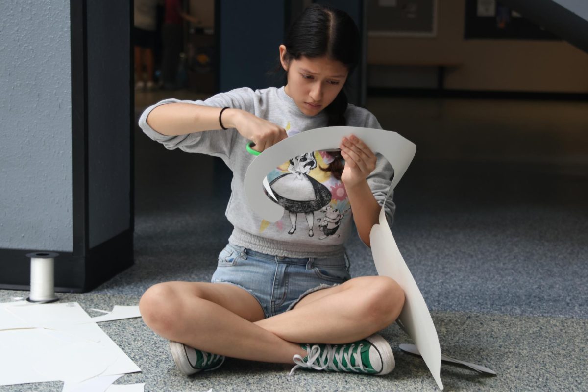 Scissors in hand, sophomore Natalia  Castillejos-Ramirez cuts out a sign. 