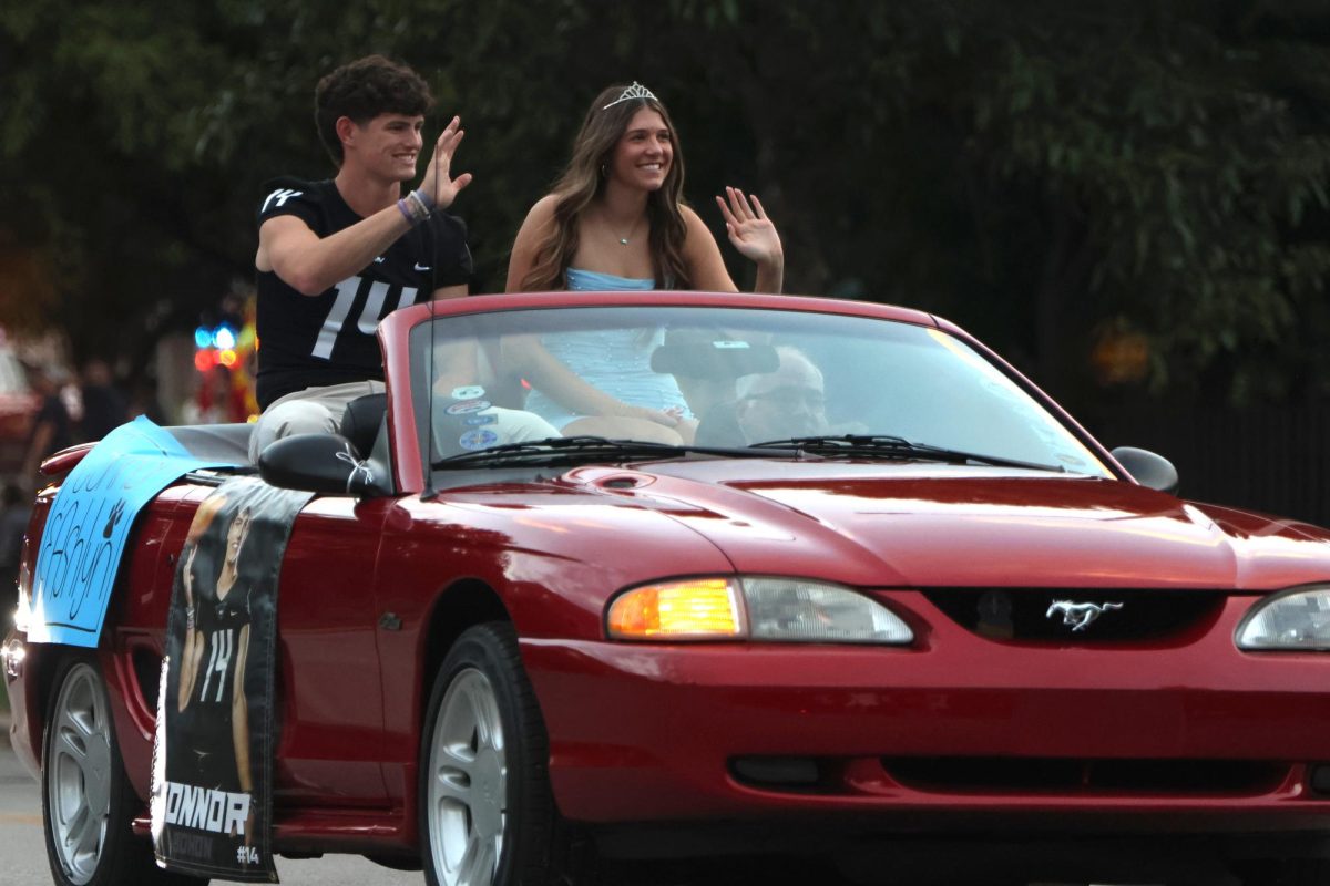 Waving to the crowd, homecoming King and Queen candidates Connor Bohon and Ashlyn Blazer ride in the parade. 