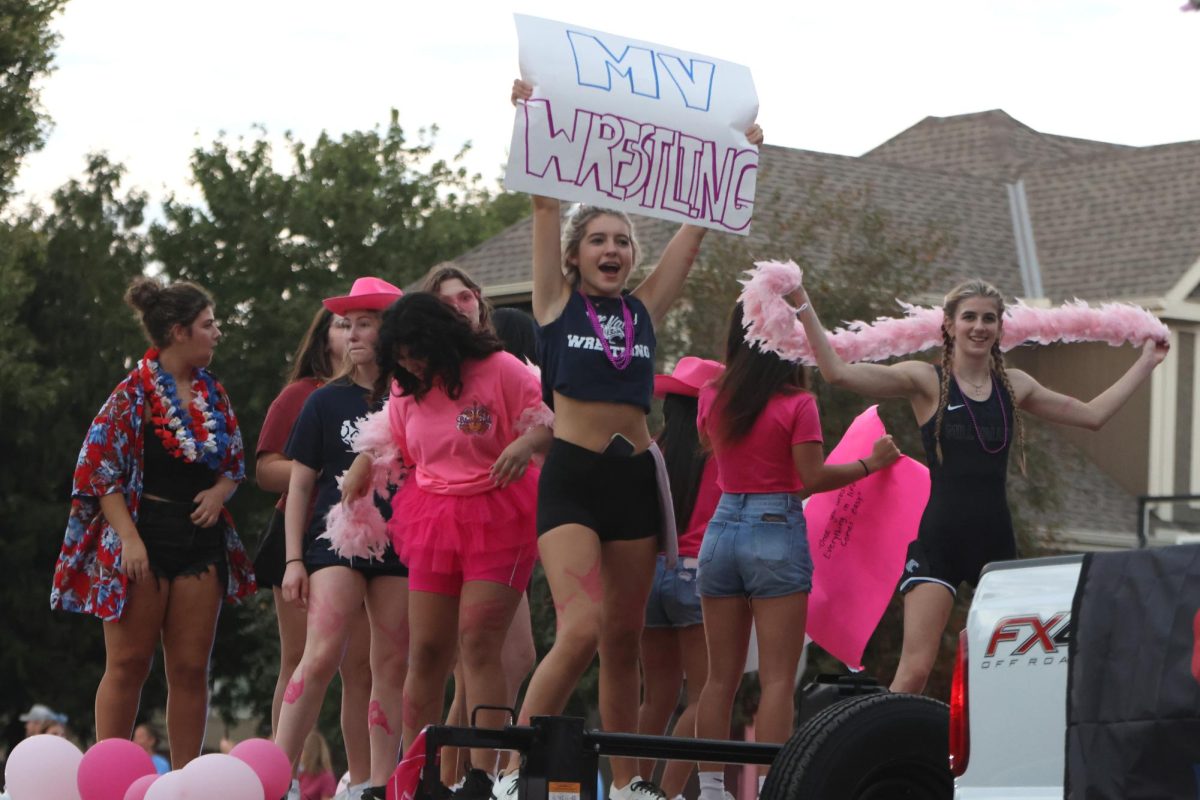 Holding a "MV Wrestling" sign junior Addison York rides the girls wrestling float. 