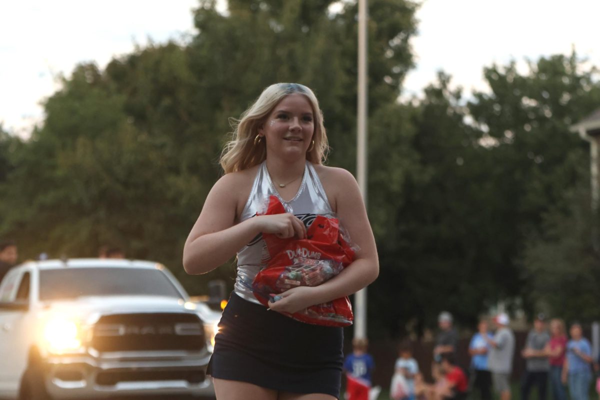 Handing out candy, junior Sydney Lenon walks with the Silver Stars in the homecoming parade. 
