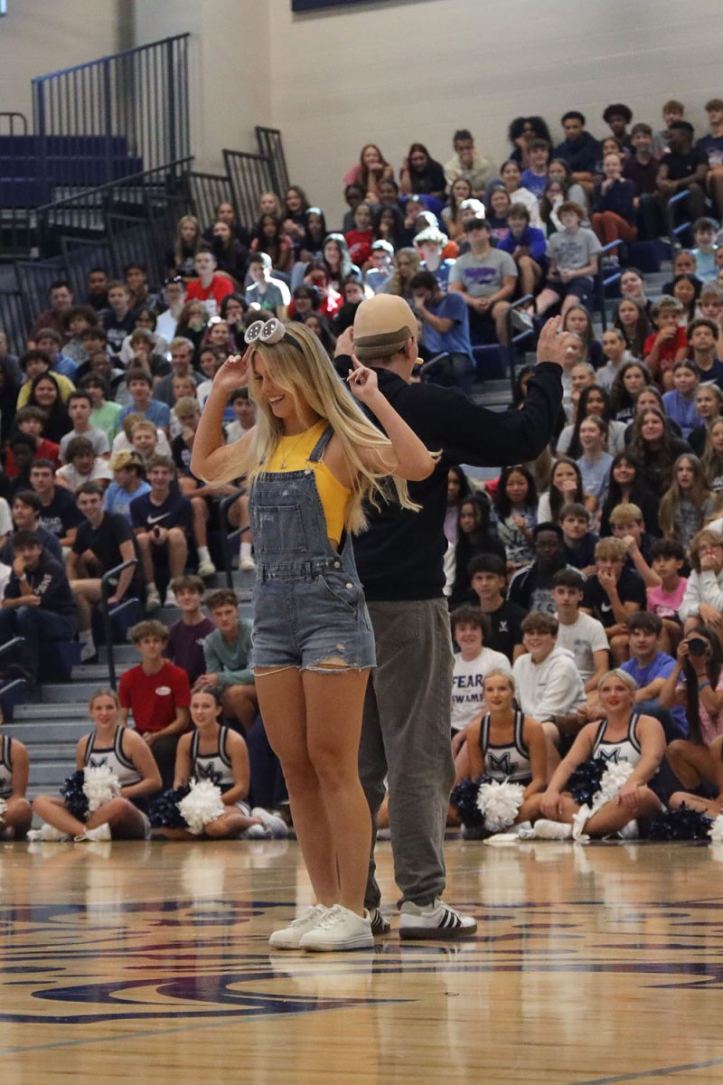 Pointing up, senior Addison Long performs her handshake with her partner, senior Blake Gray.