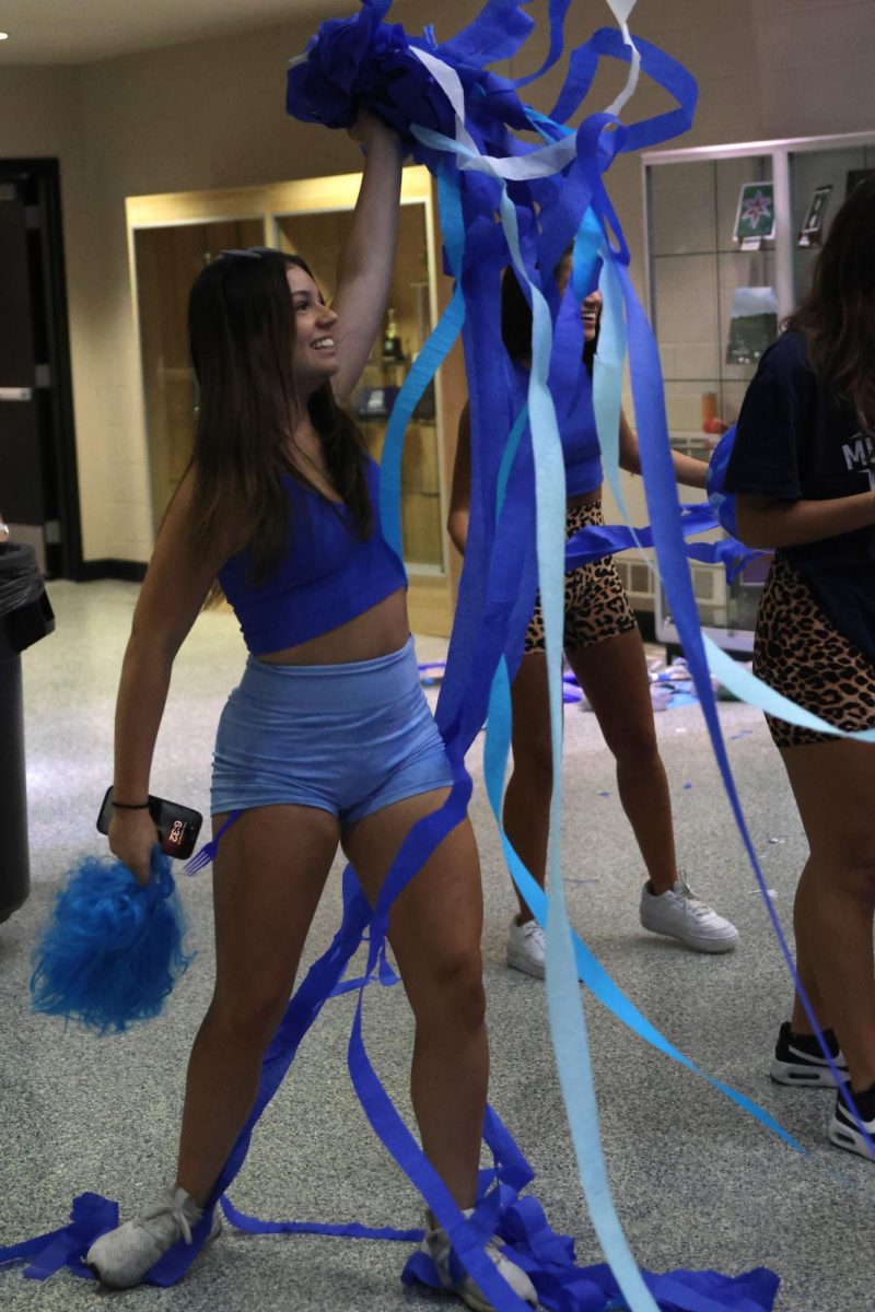 Senior Rylie Maguire dances while picking up streamers during the Blue Bomb celebration.
