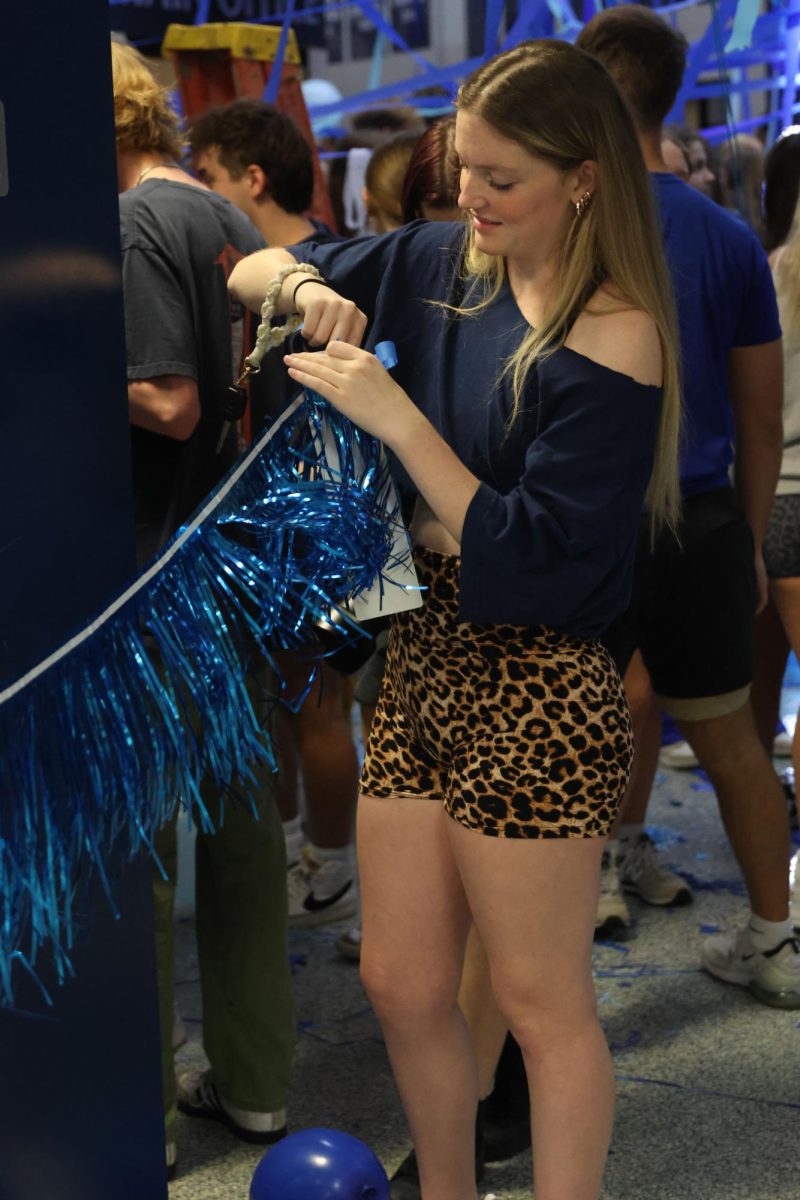 Peeling away the sticker, senior Juliya Laws hangs up decorations around the lockers.
