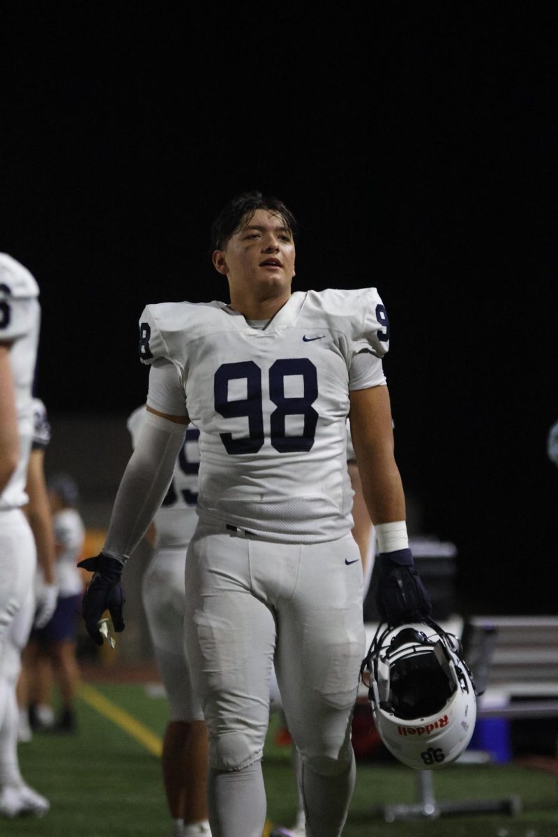 Carrying his helmet, Junior Jackson Lucht walks over to his teammates.