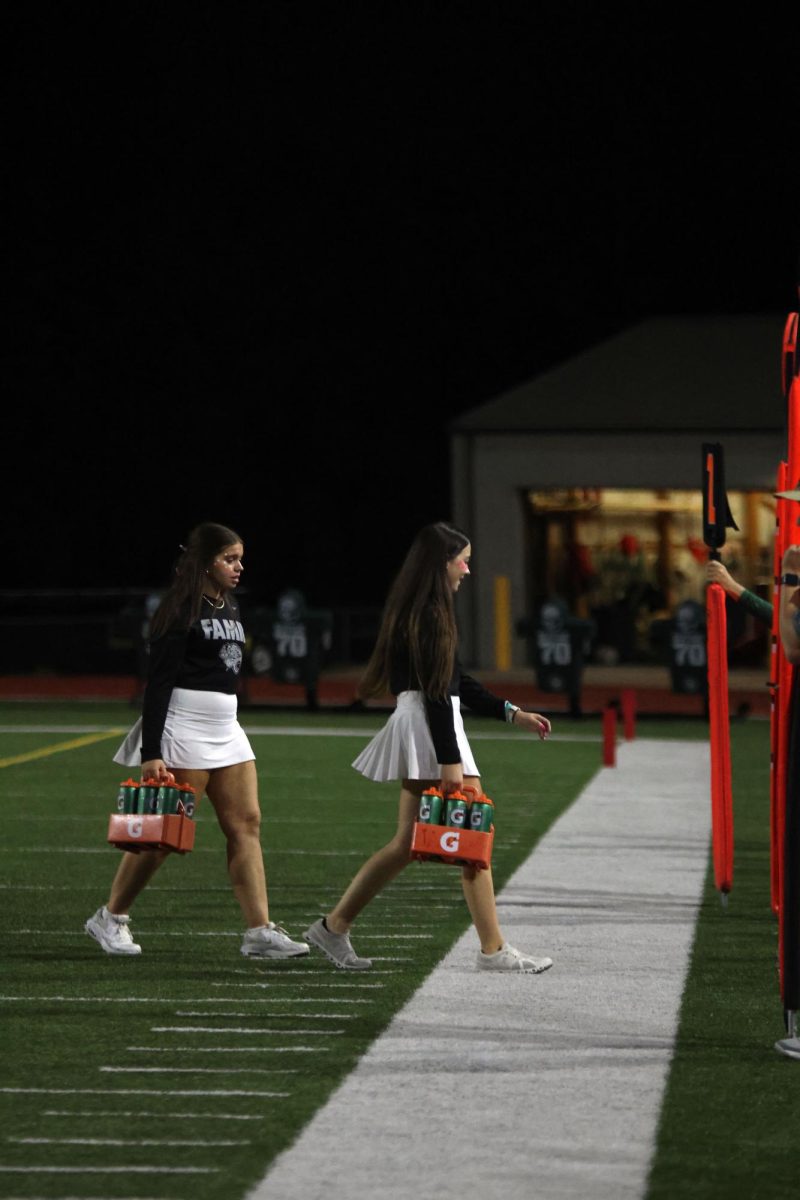 After a huddle, junior Abby Allen and sophomore Cassidy Stuke carry waters back to the sideline.