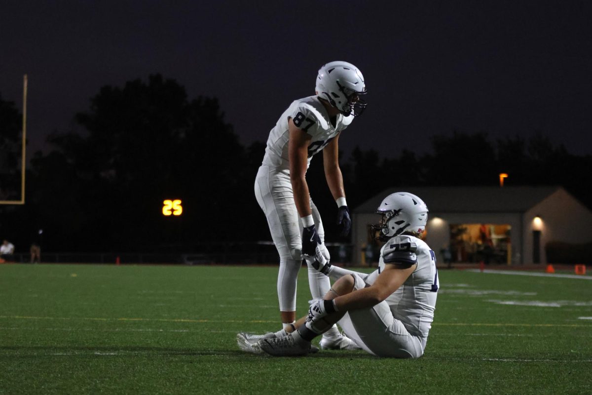 Senior Isaac Sauder helps senior Aiden Lehr after a play to make sure he's okay.