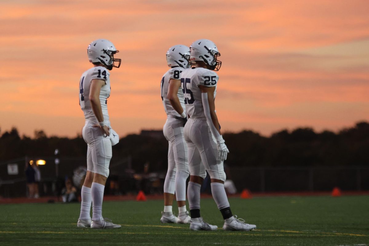 Seniors Connor Bohon, Isaac Sauder and junior Reggie Reece wait for their team on the field.