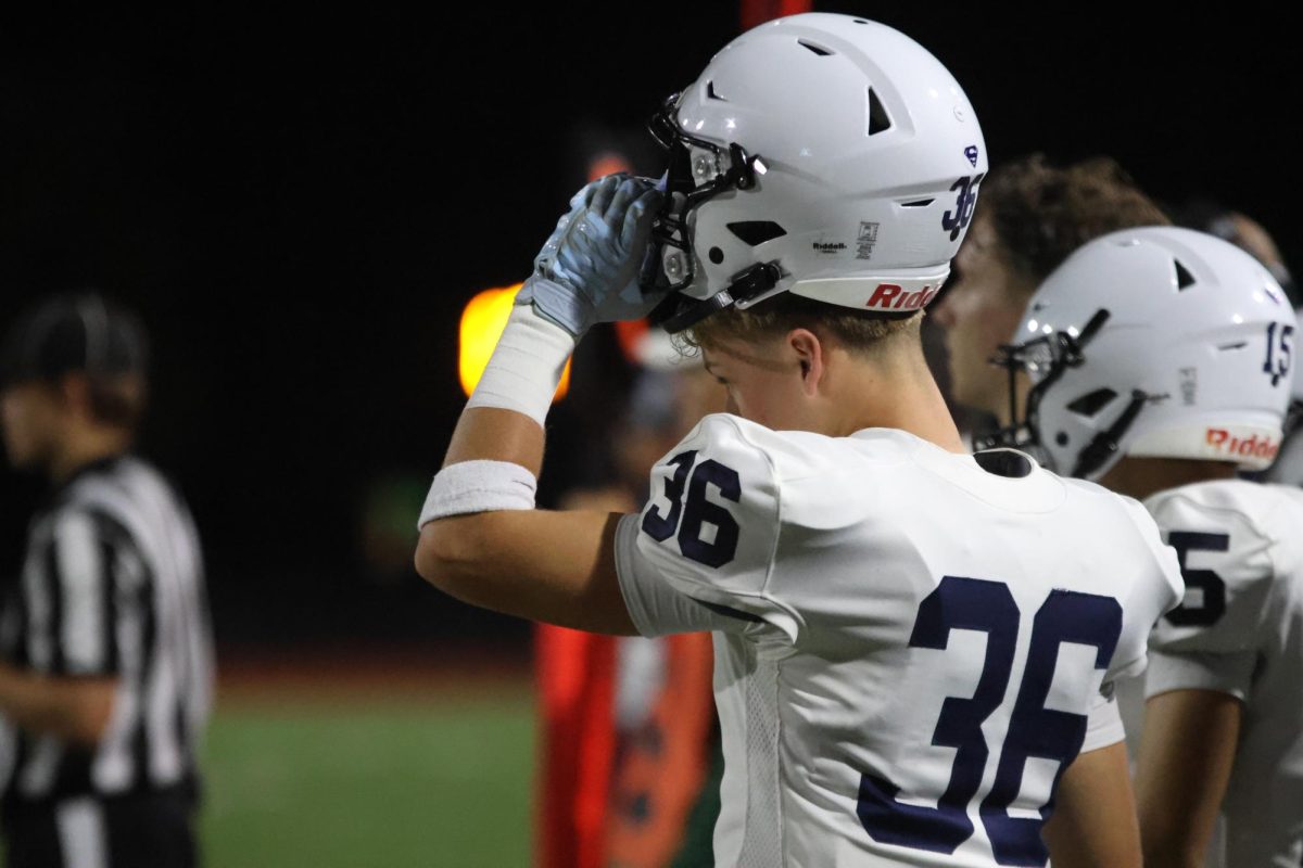 Getting ready to play, sophomore Kendyn Charbonneau puts on his helmet.