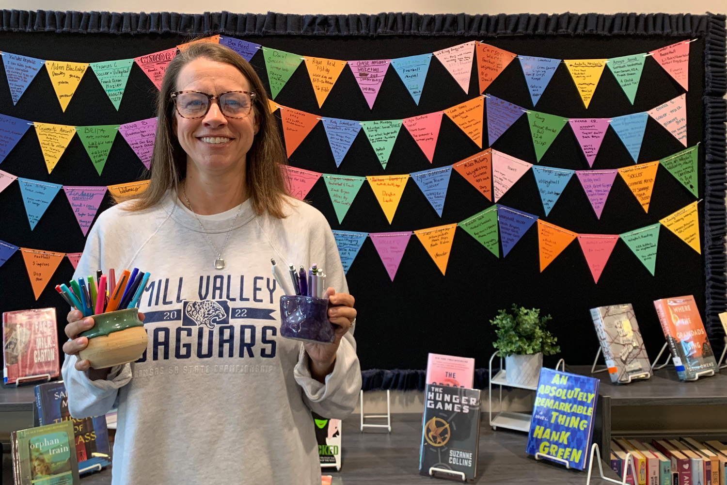 Media Specialist Ashley Agre stands in front of the freshman get to know you banners in the library.