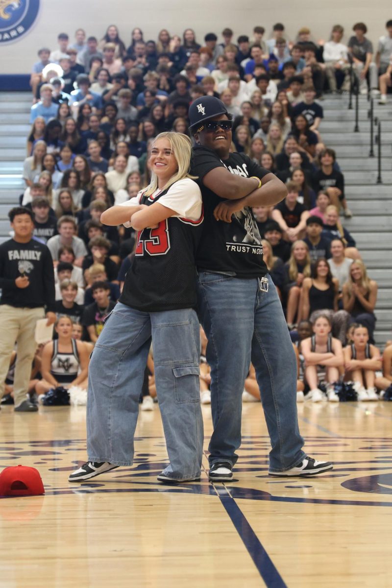 Standing back to back, seniors El-Roi Hasabu and Logan Miller cross their arms after completing their candidate handshake entrance.