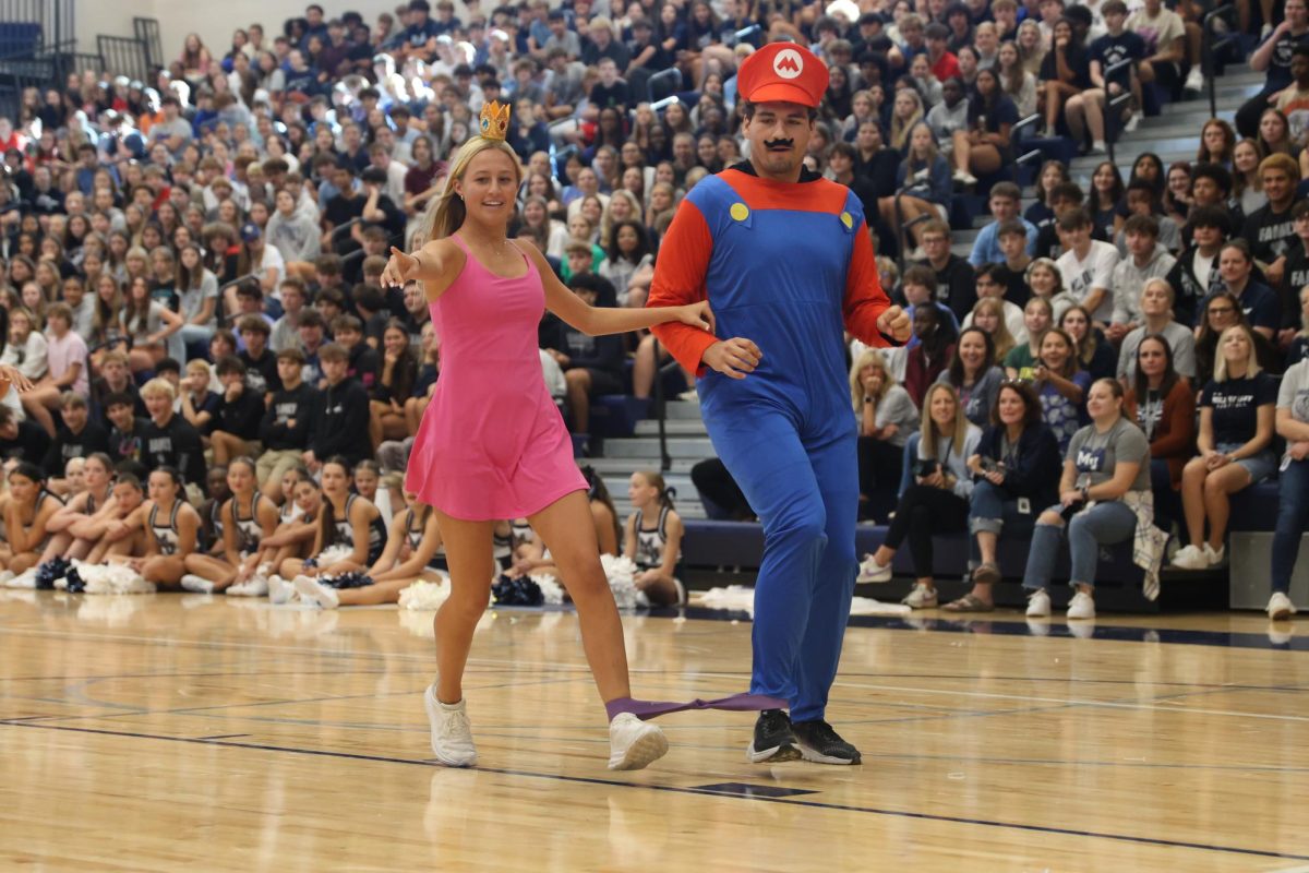 Pointing ahead, senior Maggie Wieland attempts to show her partner senior Abe Shaffer where the correct song title is.