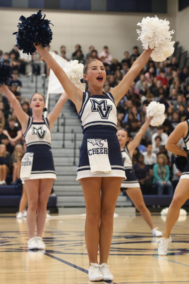 Holding her poms high, junior Sydney Epperson performs a routine with the team.