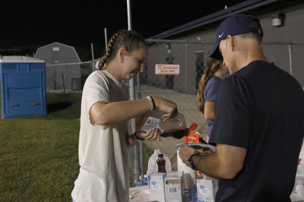 Junior Sydney Nash pours maple syrup on a supporter's pancakes.