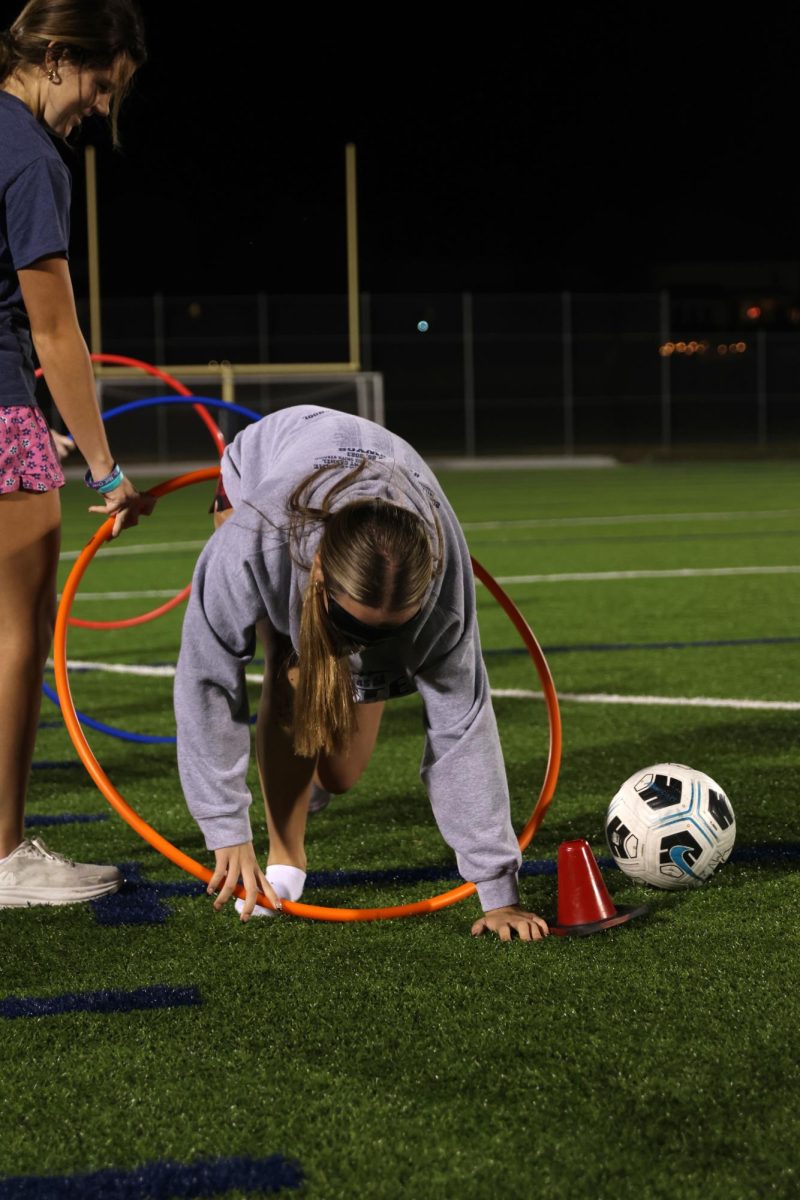 Sophomore Gracyn Schreiber crawls through a hula hoop quickly before moving on to the next obstacle.