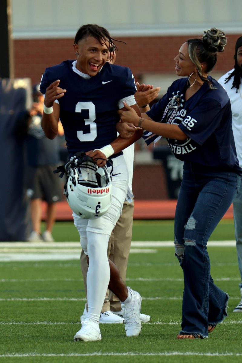 Walking across the field on senior night, senior Desmon Williams waves to the student section.