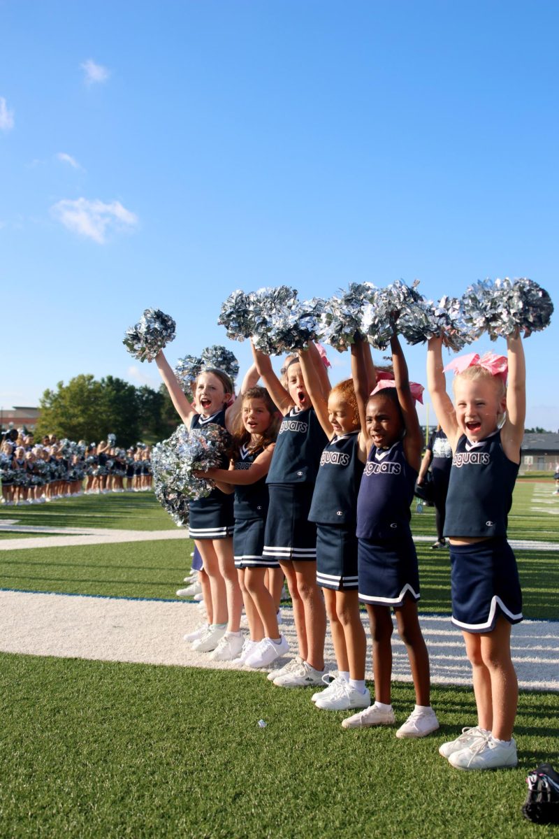 Ready for the players to run out, Junior Jag cheerleaders hold their poms up with a smile.