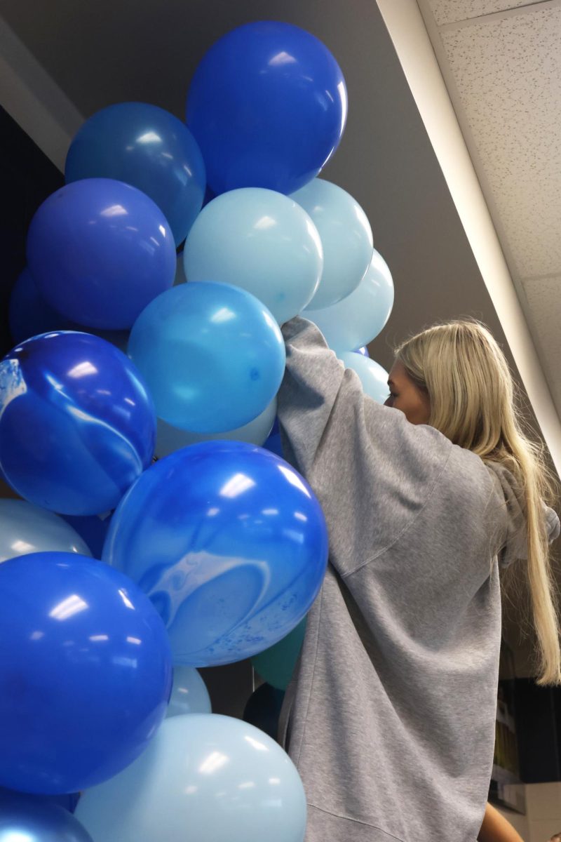 Hanging balloons, junior Callaway Clifton makes an arch above the doorway to the auxiliary gym.