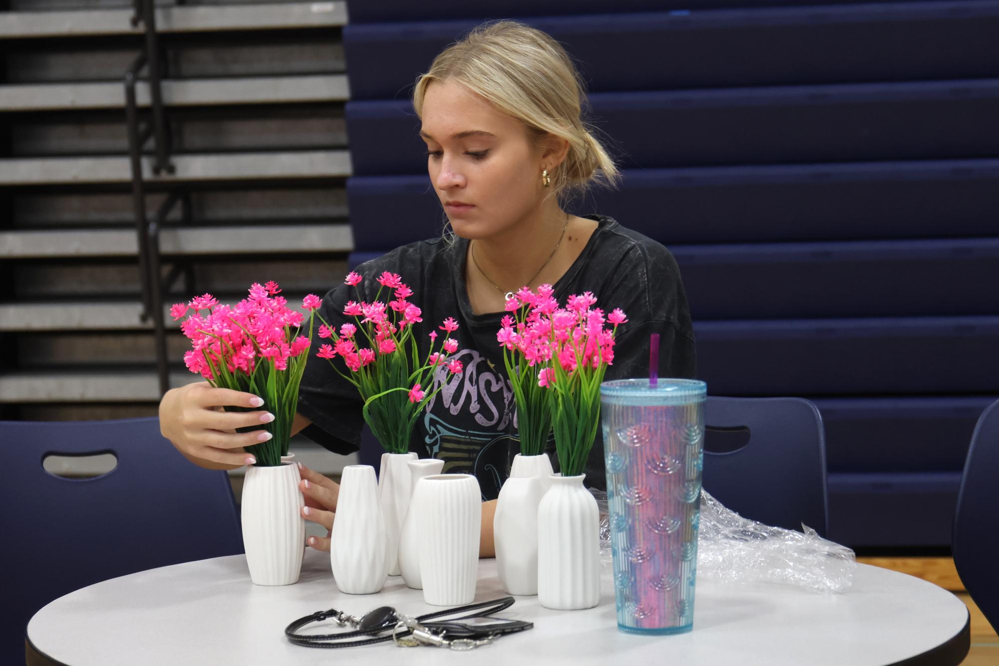 Potting flowers, sophomore Reese Miller doctorates the tables in the auxiliary gym.