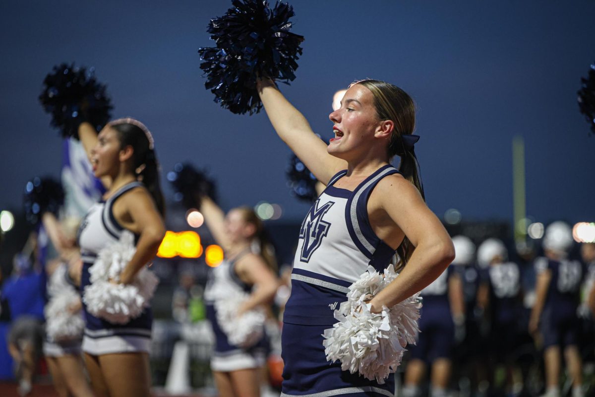 With her pom in the air, junior Racheal Johnson cheers during the football game. 