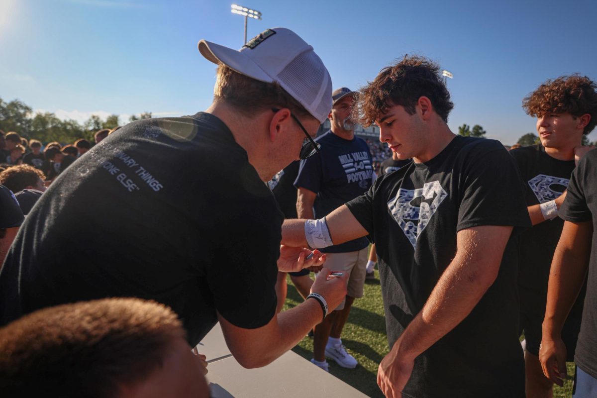 With a pen in his hand, senior Garret Clark signs sophomore Brayden Wingerd’s elbow tape at the senior signing table. 